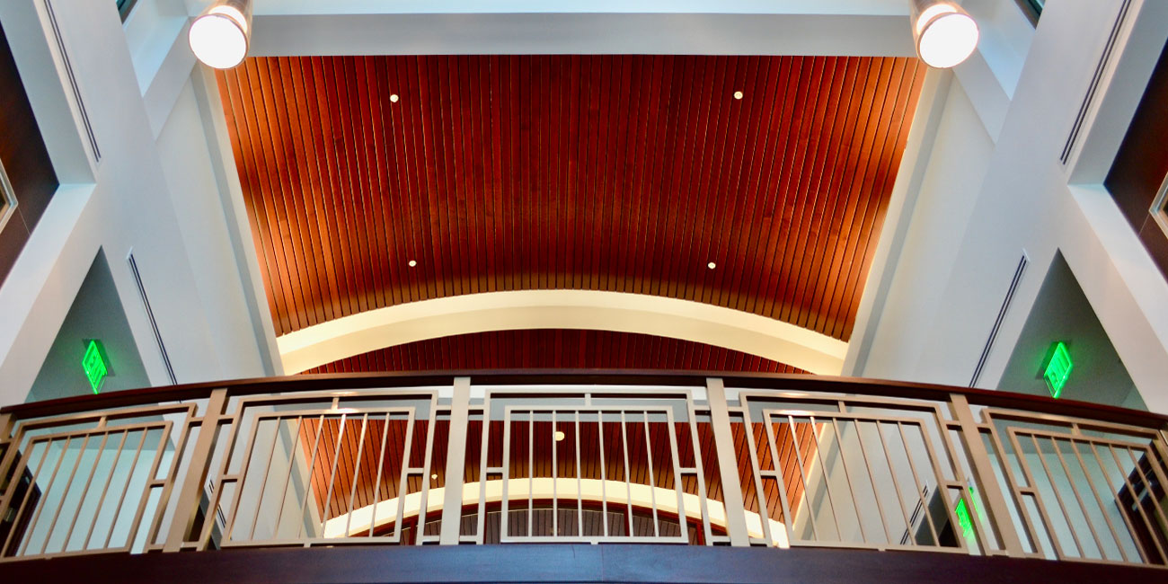 Large wood barreled ceiling of office building atrium with a view looking up to the second floor landing